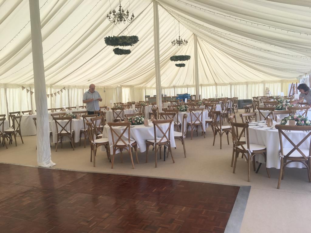 A large tent with tables and chairs set up for a wedding reception.