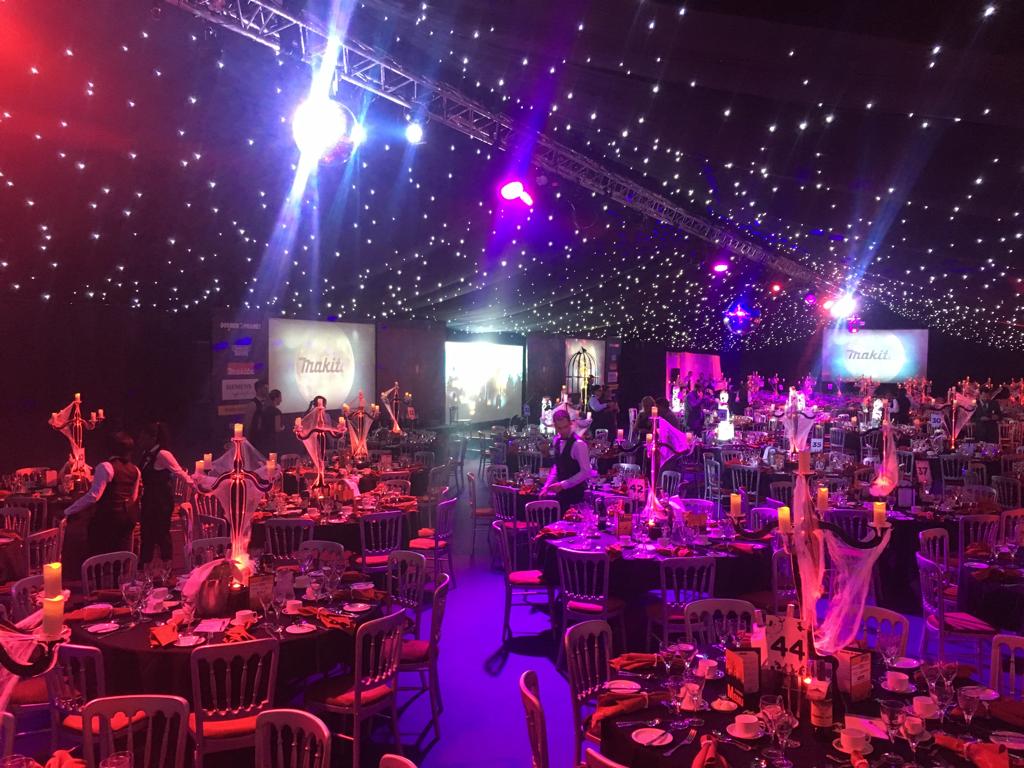 A large room filled with tables and chairs and purple lights.