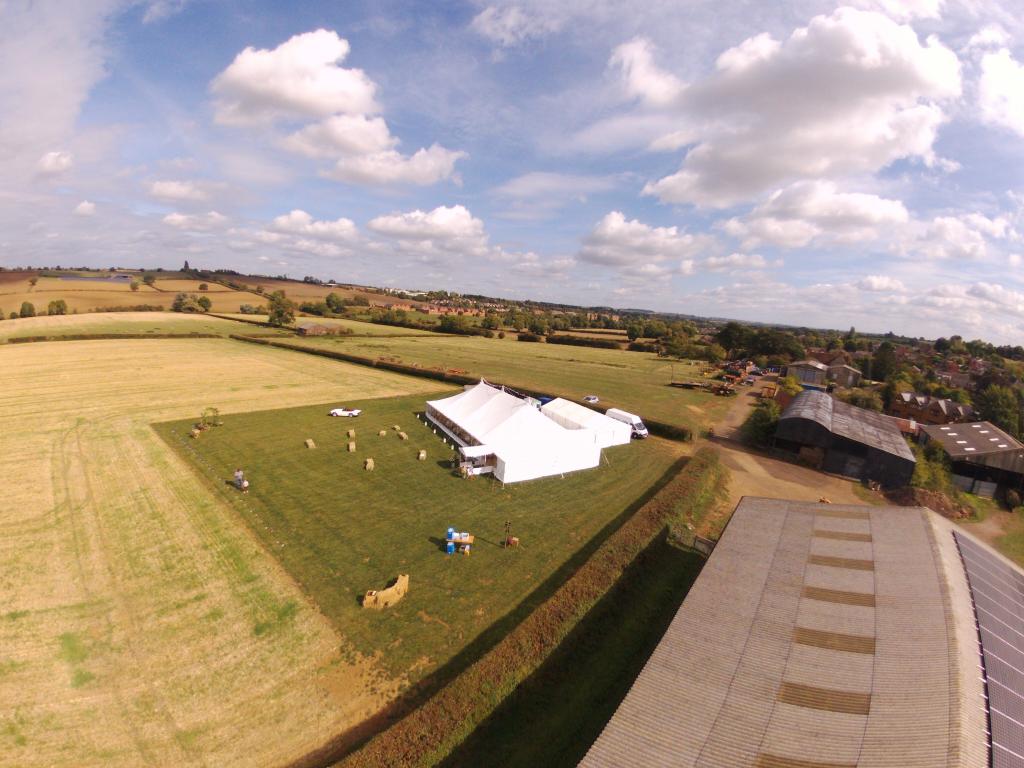An aerial view of a large white tent in a field