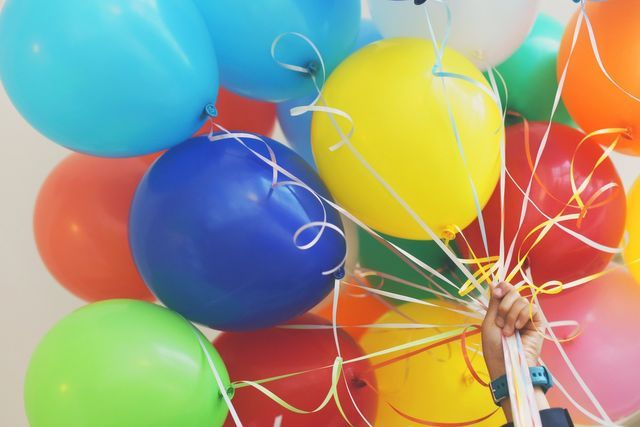 A person is holding a bunch of colorful balloons in their hand.