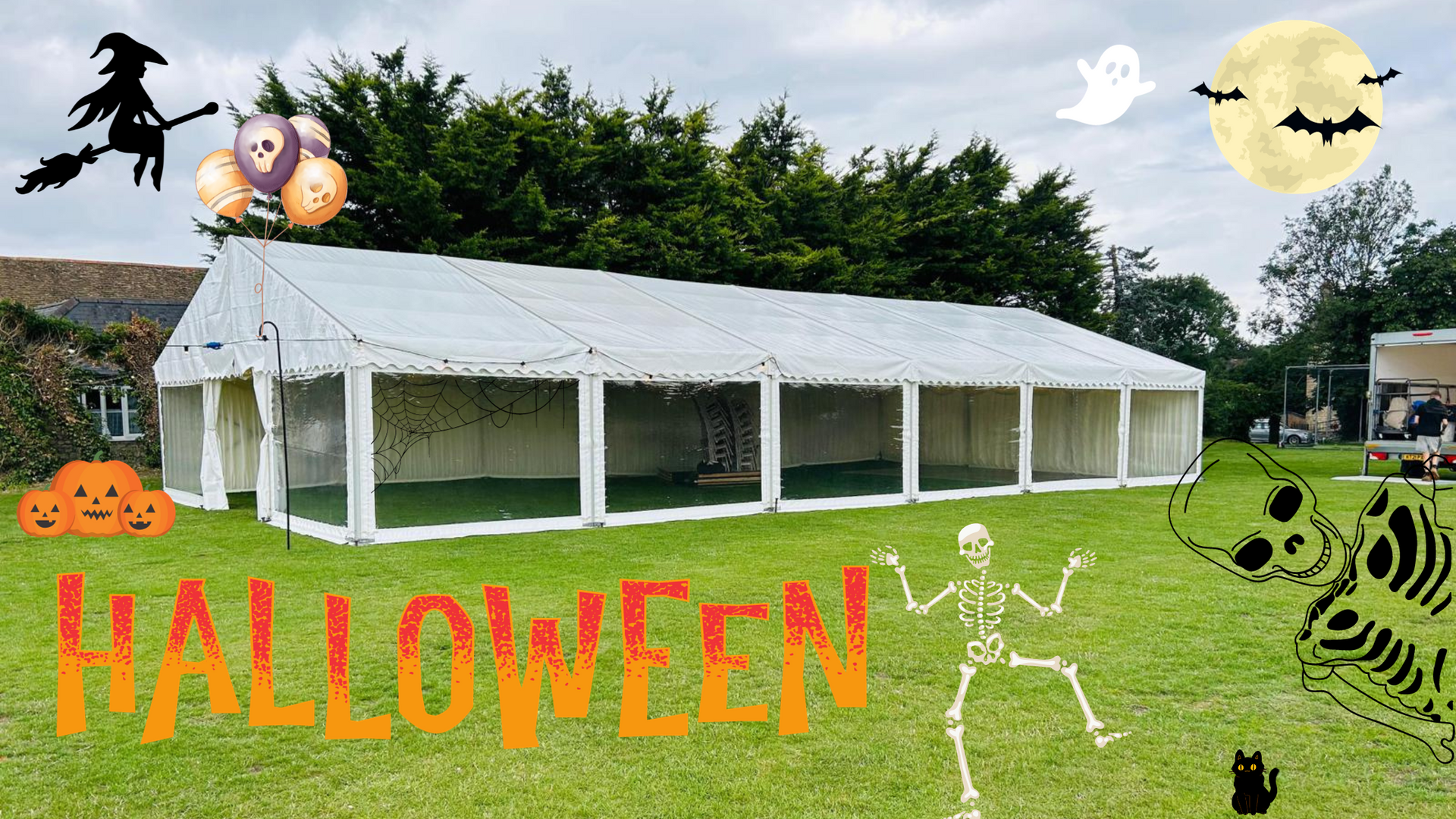 A large white tent is in the middle of a grassy field decorated for halloween.