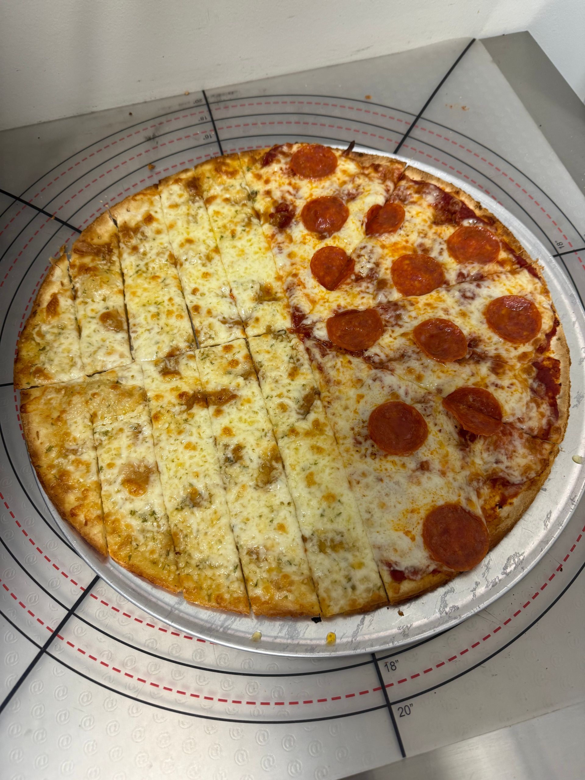 Half cheese, half pepperoni pizza on a clear, round serving plate.