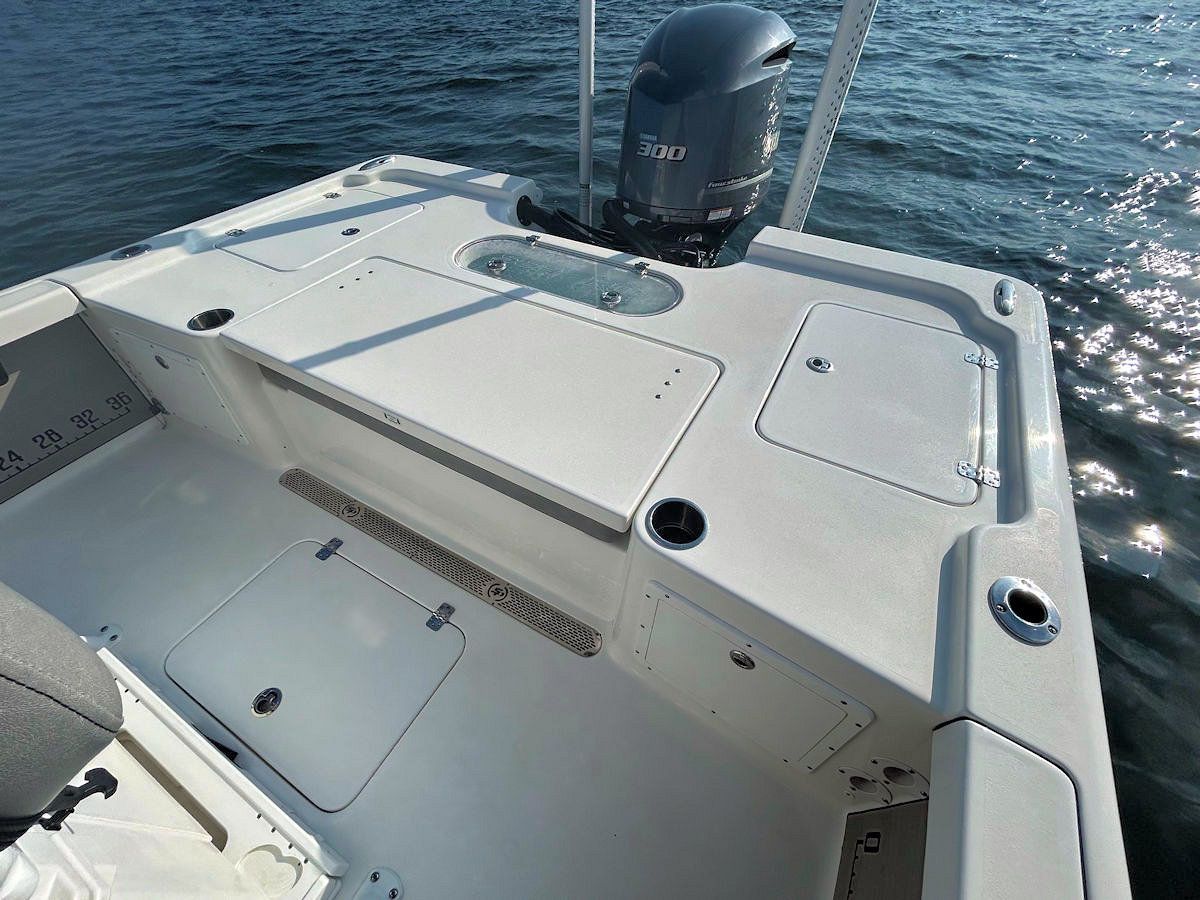 Interior view of a white fishing boat with an outboard motor, on the water.