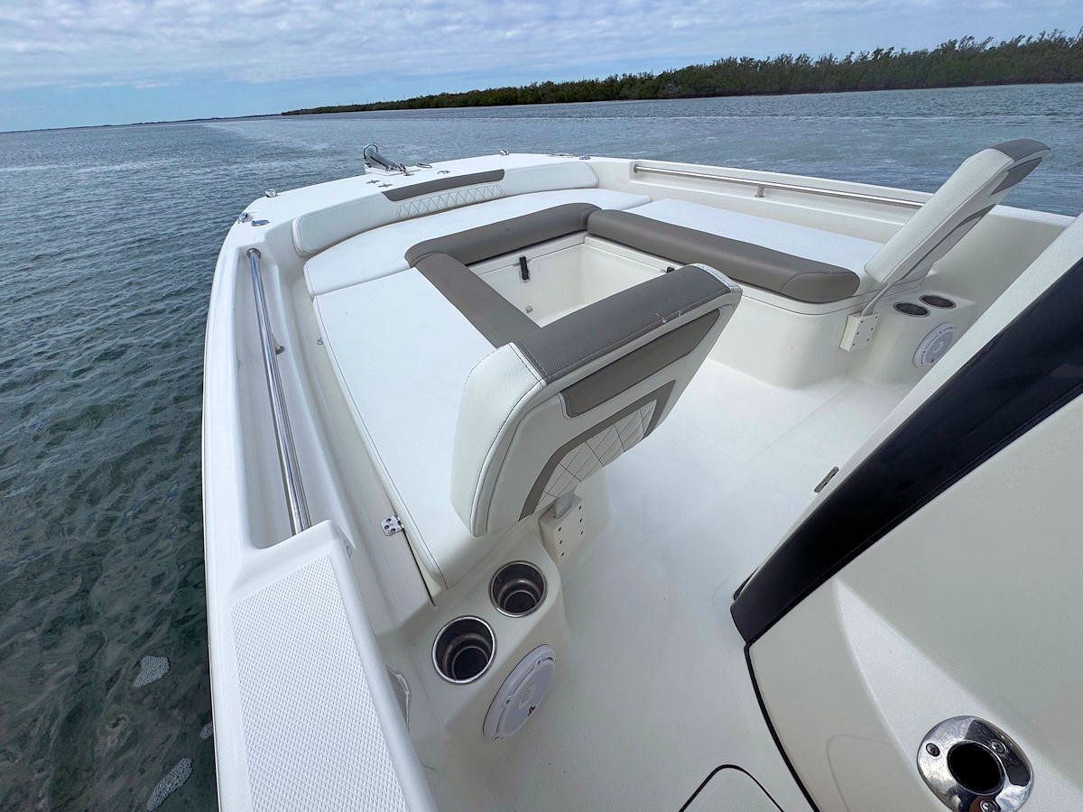 White boat interior with gray cushions, cup holders, and a view of the water.