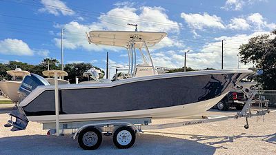 Blue and white boat on a trailer, under a partly cloudy sky.