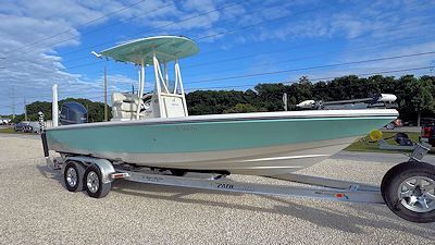 A light blue and white fishing boat on a trailer, under a partly cloudy sky.