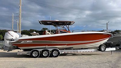 Orange and white speedboat on a trailer, under a cloudy sky.