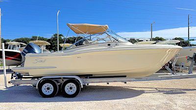 Beige motorboat on a trailer, parked on a sunny day.