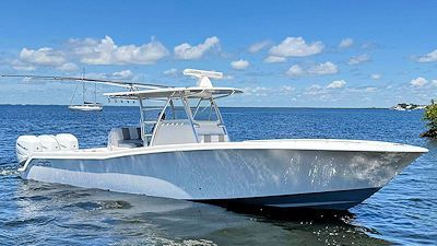 White boat on blue water with a radar and three outboard motors. Sunny day.