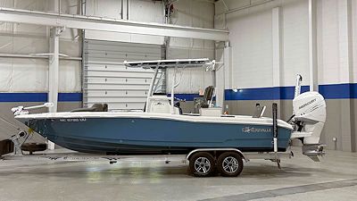 Blue and white motorboat on a trailer inside a building with a white ceiling and walls.