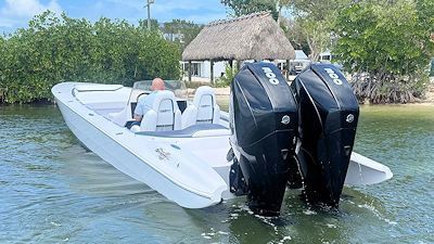 A white boat with two engines is floating on top of a body of water.