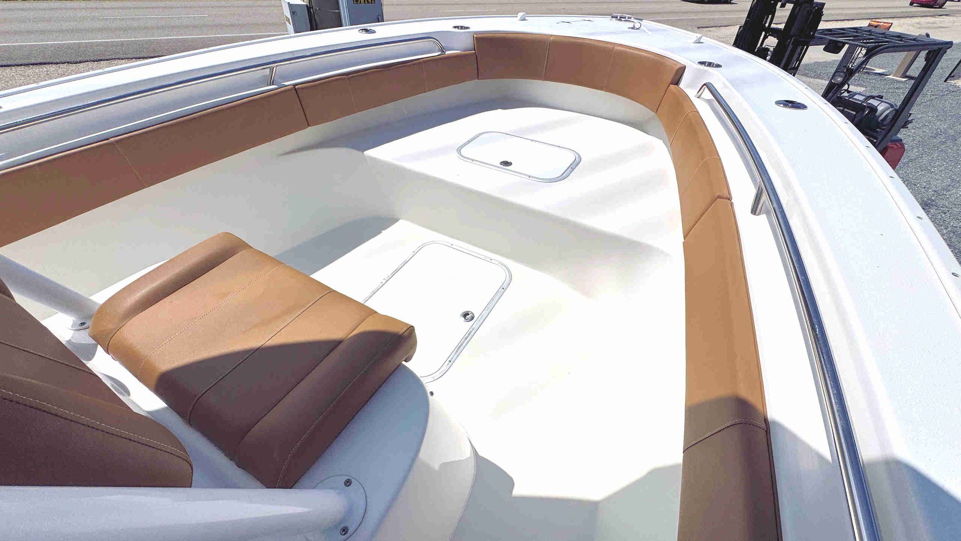 White bow area with tan cushions and a small brown seat under bright sunlight