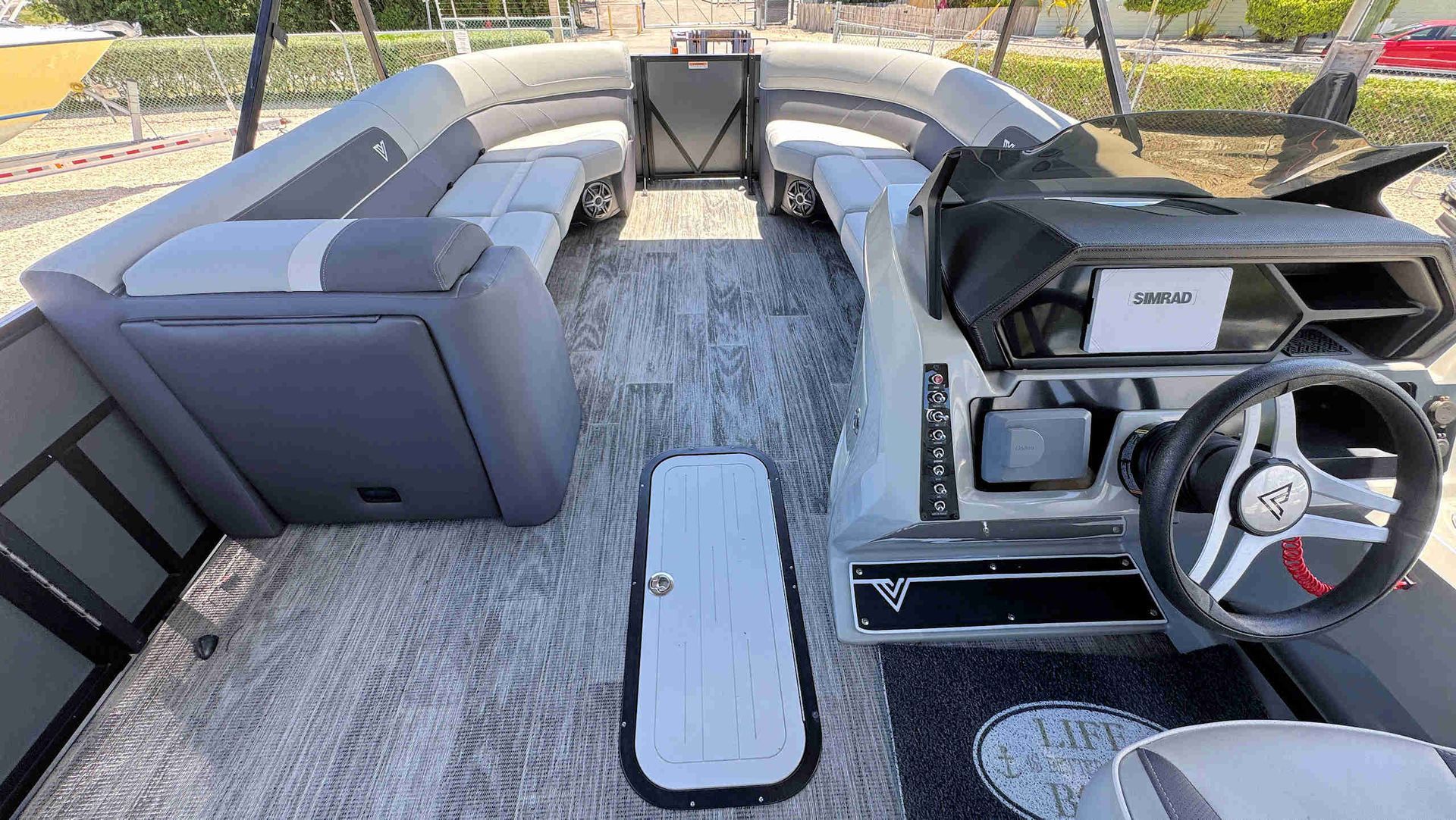 Tritoon boat interior with gray seating, steering console, and open deck area