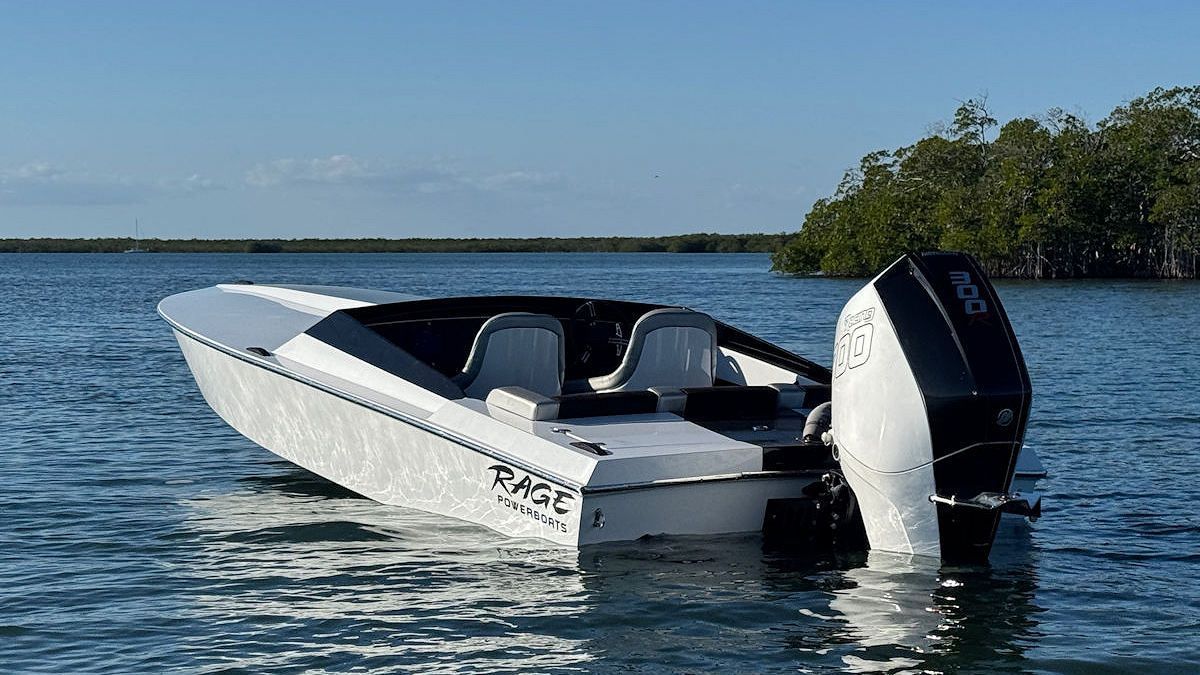 White speedboat with a black and white outboard motor on calm water, trees in the background.