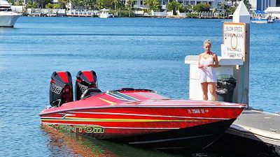 A woman is standing next to a red boat in the water.