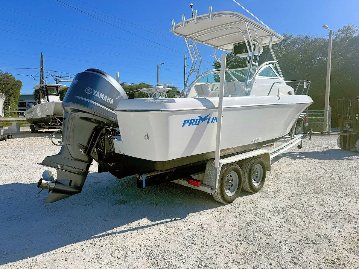 White fishing boat on a trailer, blue Yamaha outboard motor, sunny outdoor setting.