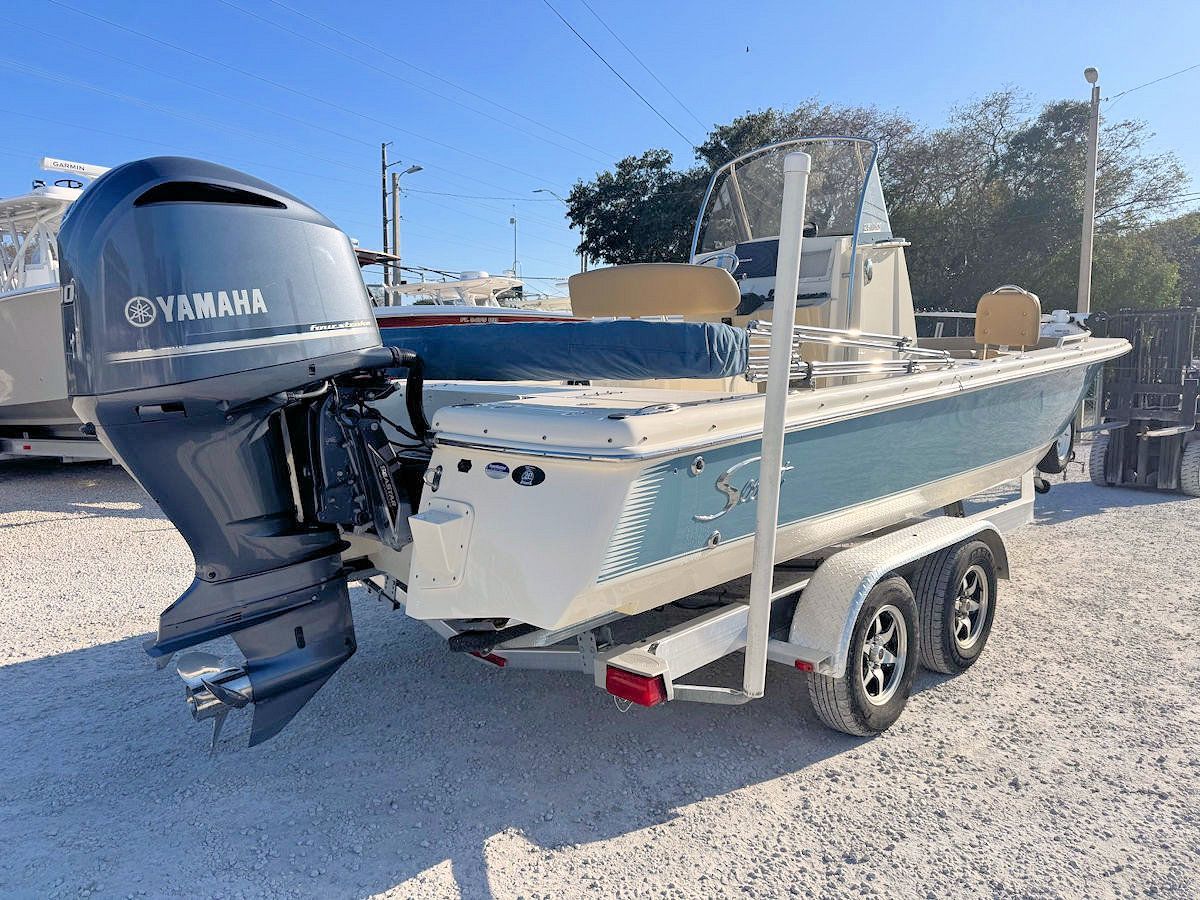 Blue and white motorboat on a trailer, parked outside on a sunny day with a Yamaha engine.