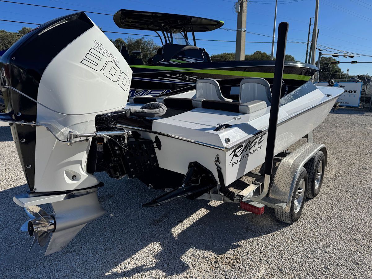 White motorboat on trailer, black engine, silver propeller, parked outside.