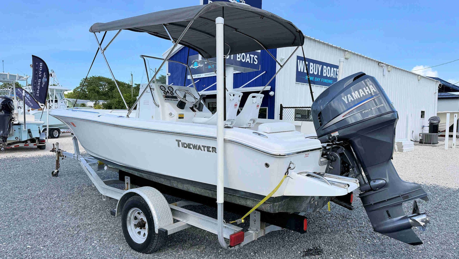 White Tidewater skiff on trailer at a gravel lot with a black canopy and Yamaha outboard motor
