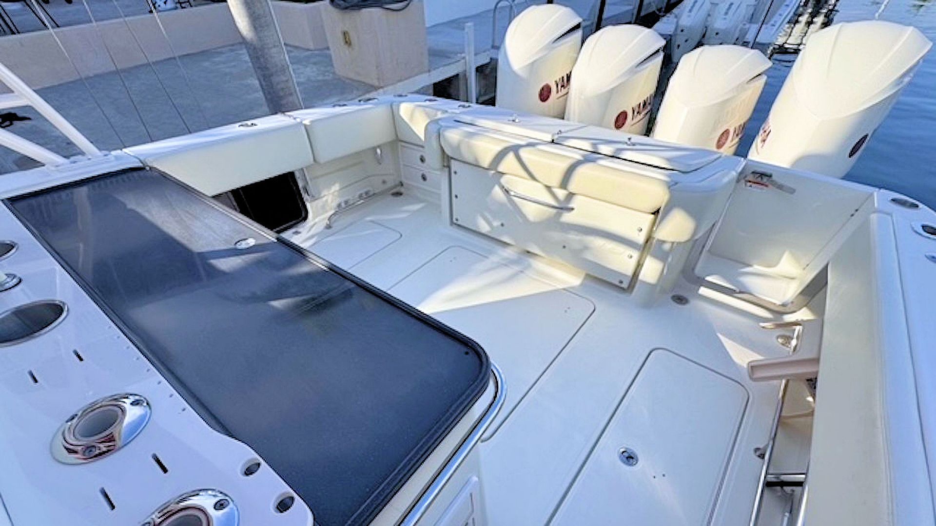 Sunlit aftdeck with white seating, navy cushions, and four outboard motors at the stern