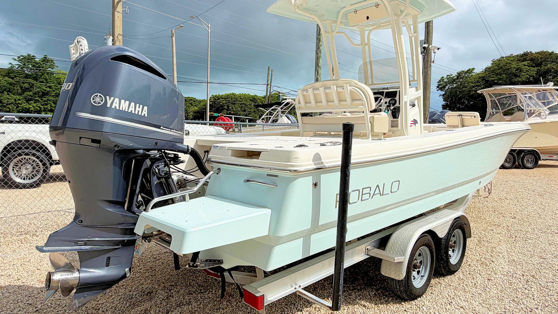 Light blue bay fishing boat on a trailer with Yamaha outboard in a gravel lot