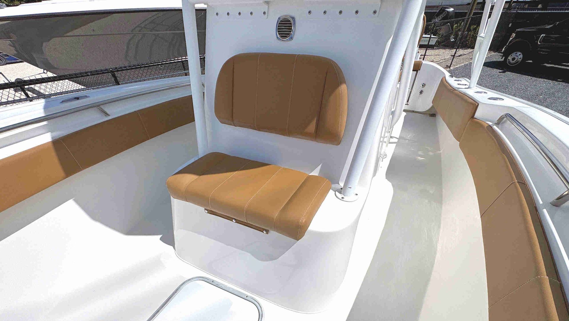 Tan upholstered center console seat on a white boat deck with tan side cushions and bright sunlight