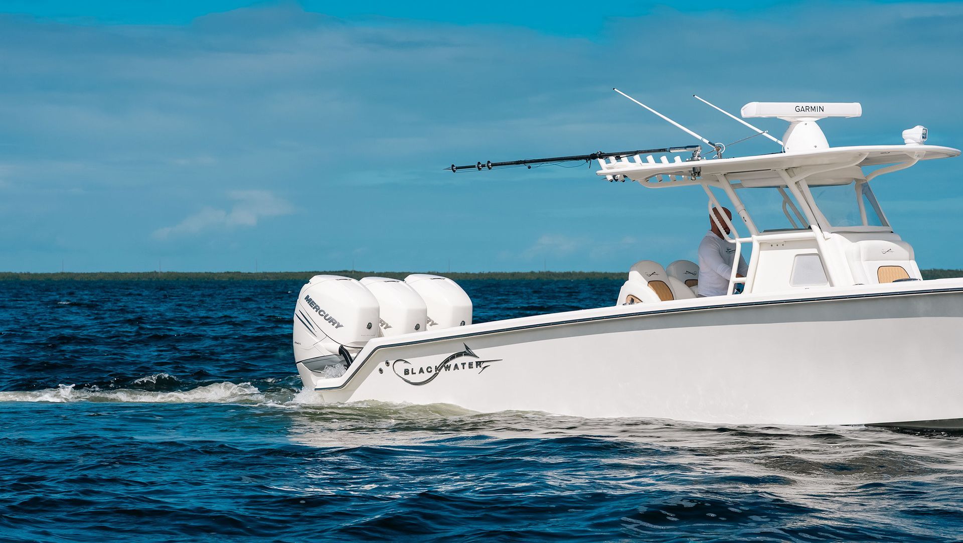 White fishing boat cruising on blue ocean under a clear sky