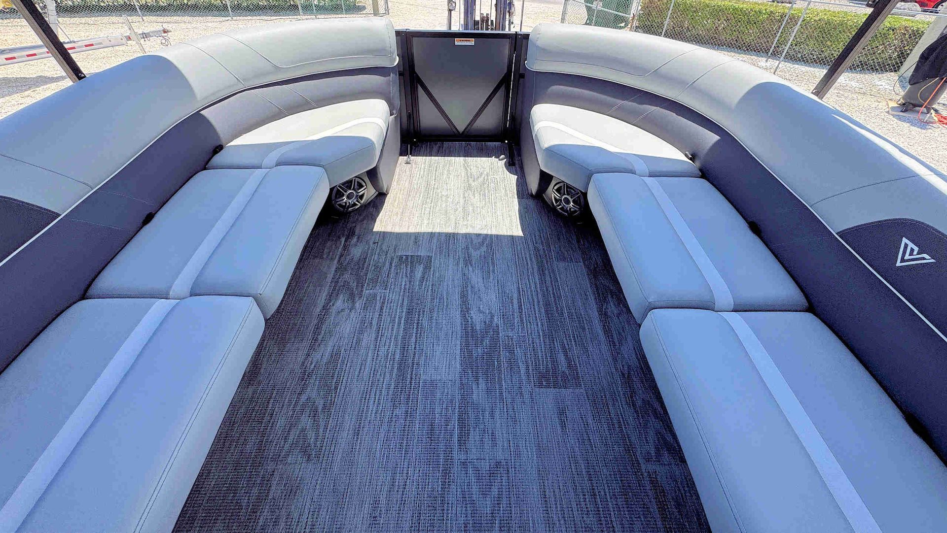 White cushioned boat seating arranged around a carpeted deck in an open outdoor setting