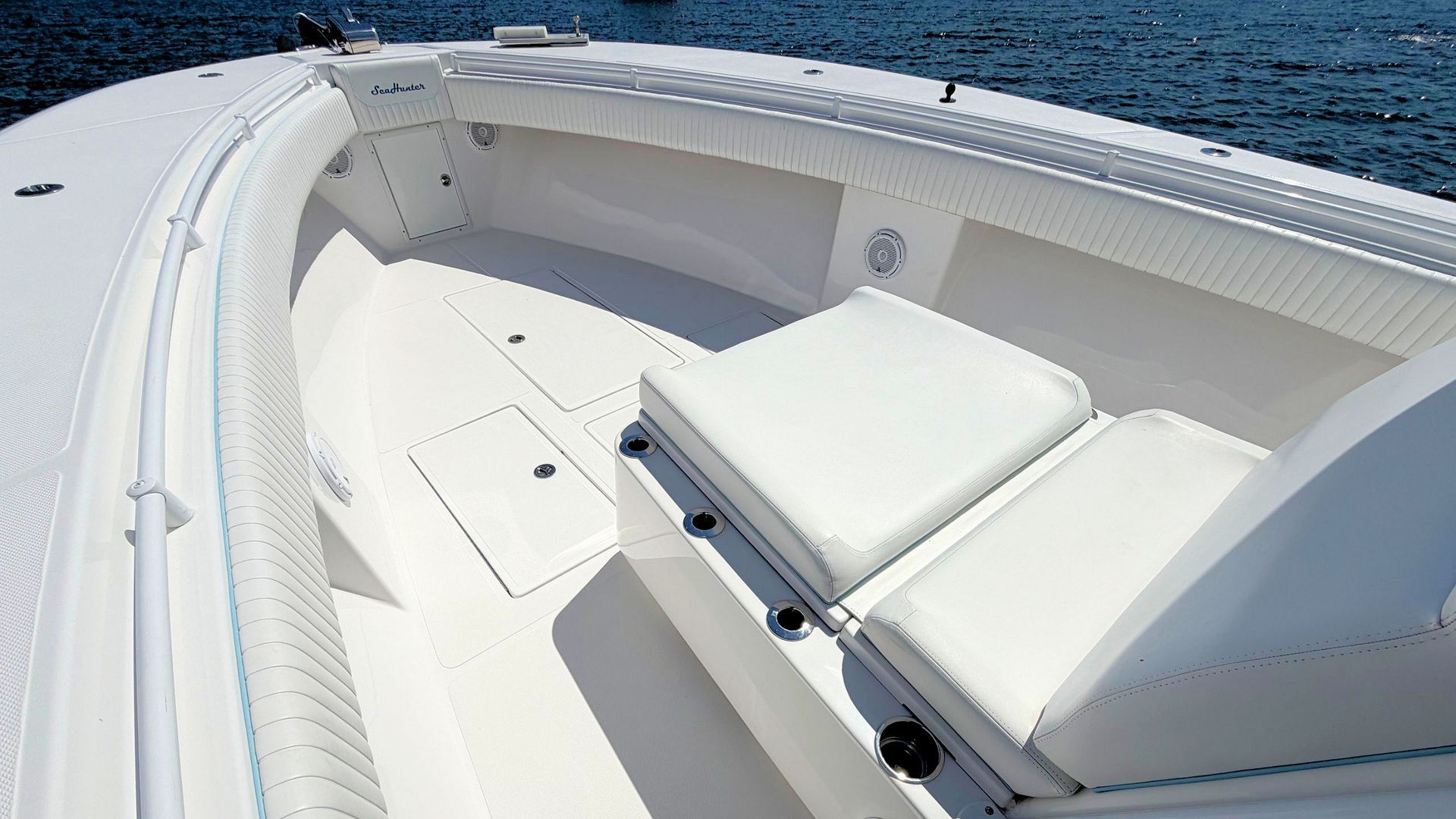 White boat seating area with cushioned benches and storage hatches on a sunny deck