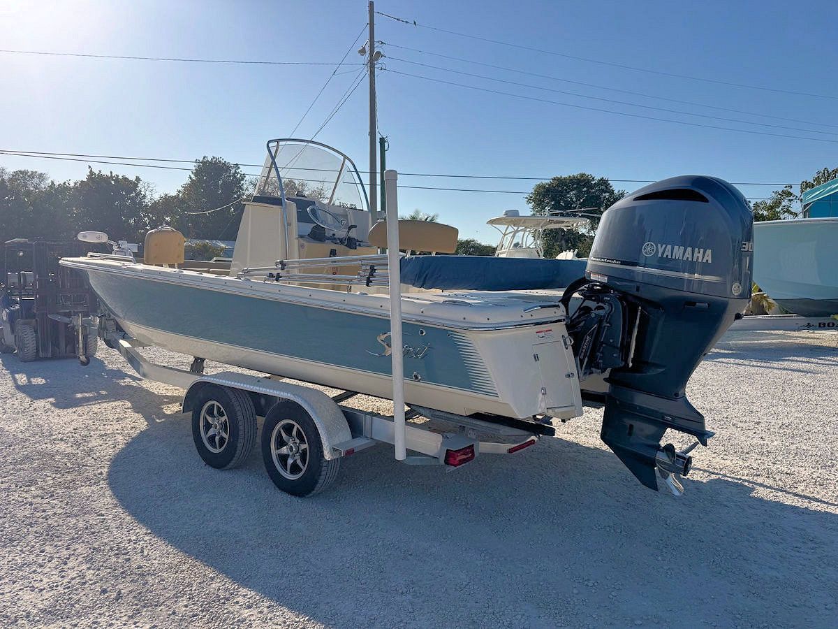 A boat on a trailer, light blue and white with a Yamaha engine, outdoors.