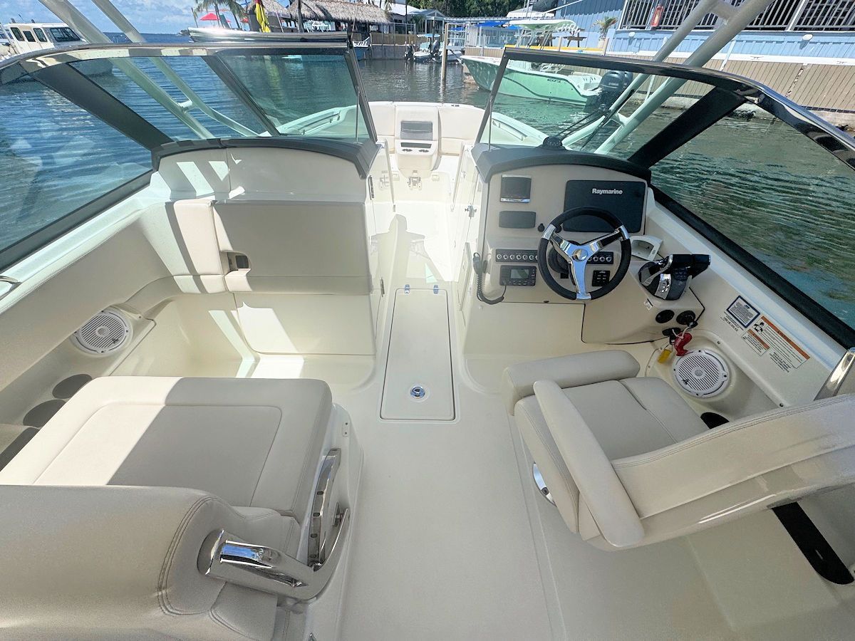 Interior view of a boat's cockpit with cream-colored seating, navigational displays, and a steering wheel.