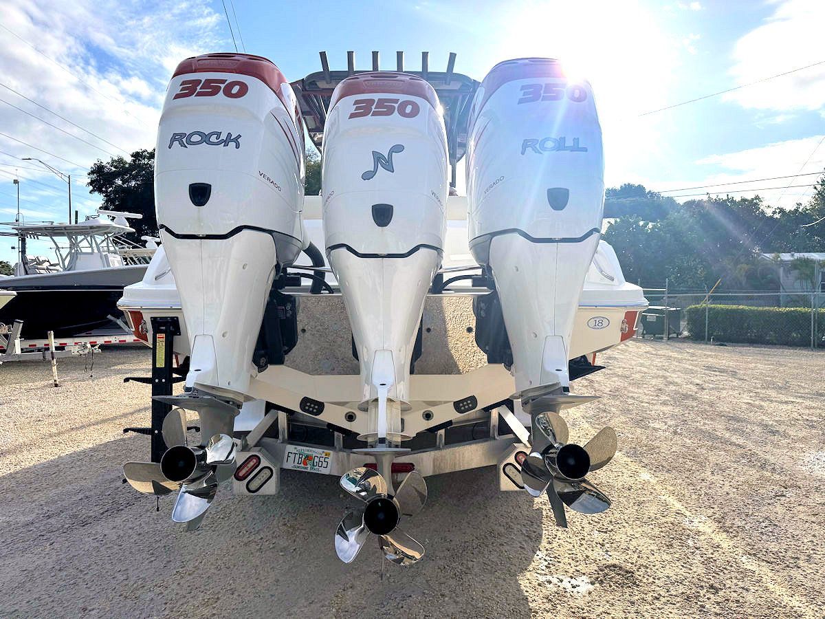 Rear view of a white boat with three outboard motors, each labeled 