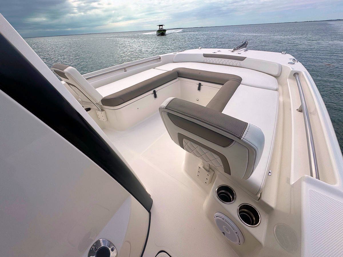 White boat deck with gray seating, looking out to sea. Another boat is in the distance.