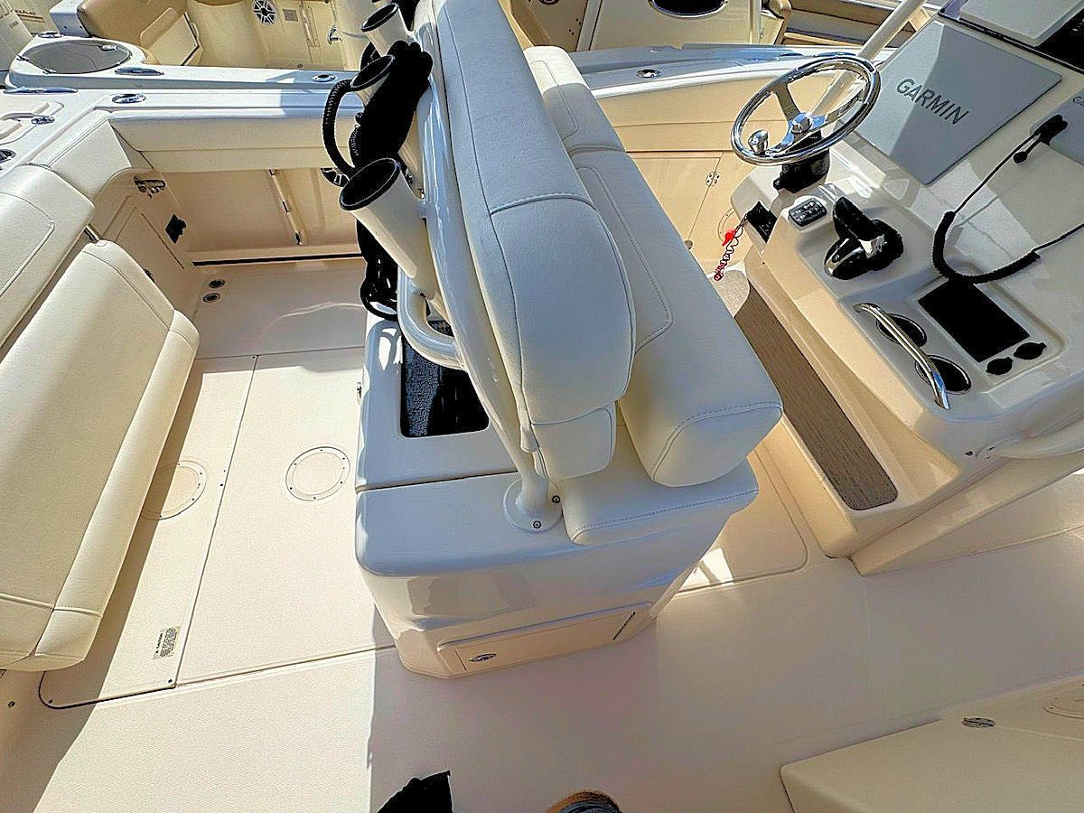 Boat interior with a cream-colored captain's chair and dashboard with controls.