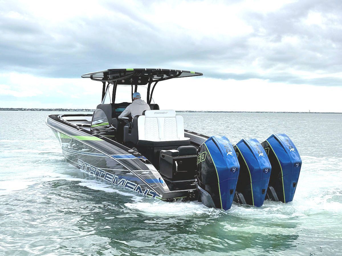 A black and blue powerboat with four engines speeds across the water.