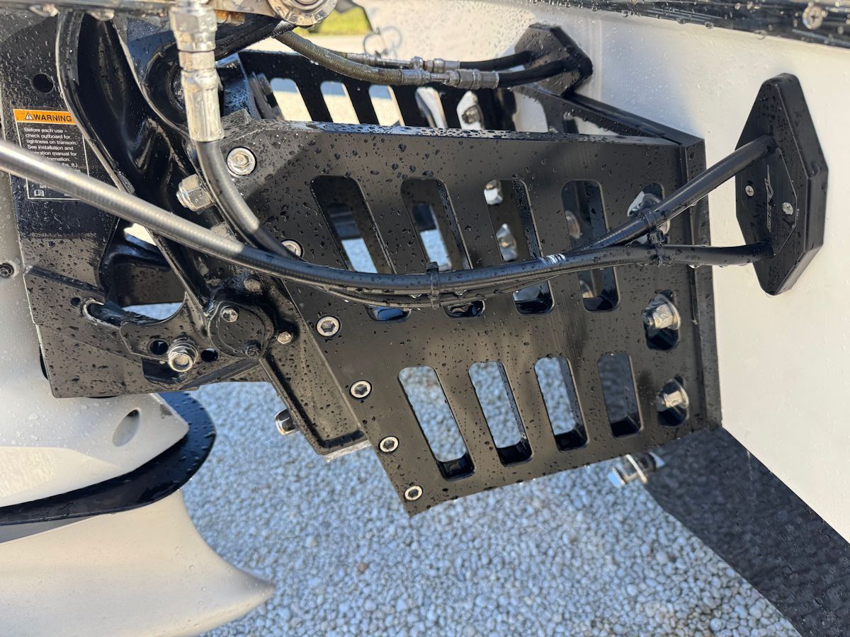 Black metal boat jack plate attached to a white boat transom.