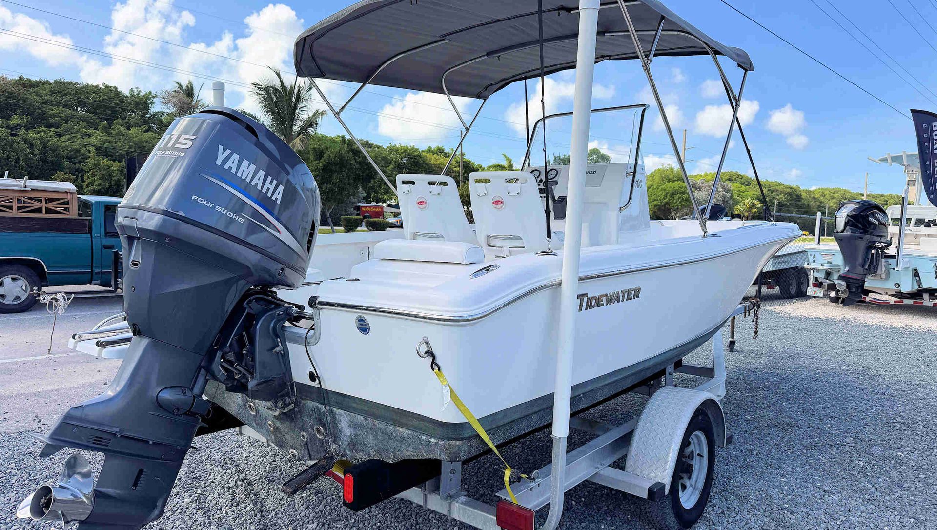 White Tidewater center-console fishing boat on a trailer with a Yamaha outboard, parked on gravel under a canopy.