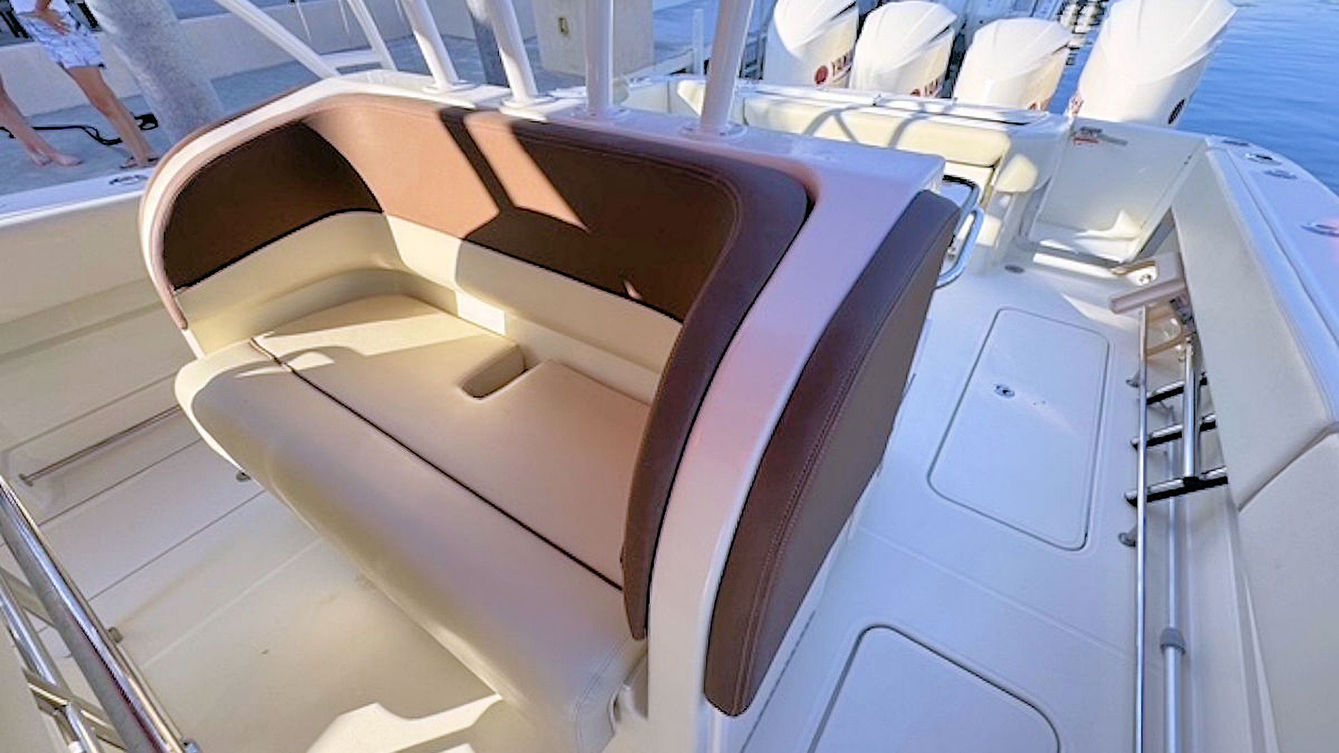 Tan cushioned captain’s bench on a white boat deck in bright sunlight