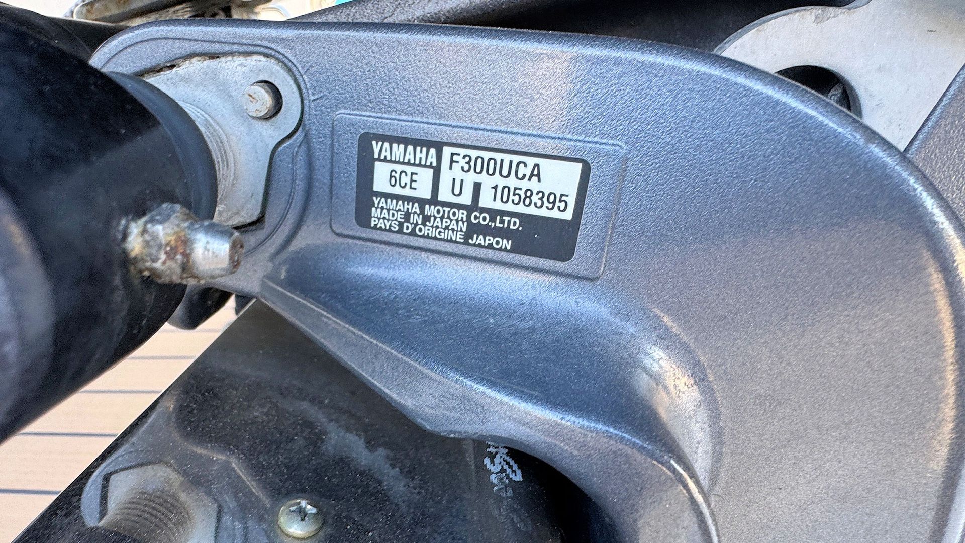Close-up of a silver metal machine part with a black handle and small identification label.