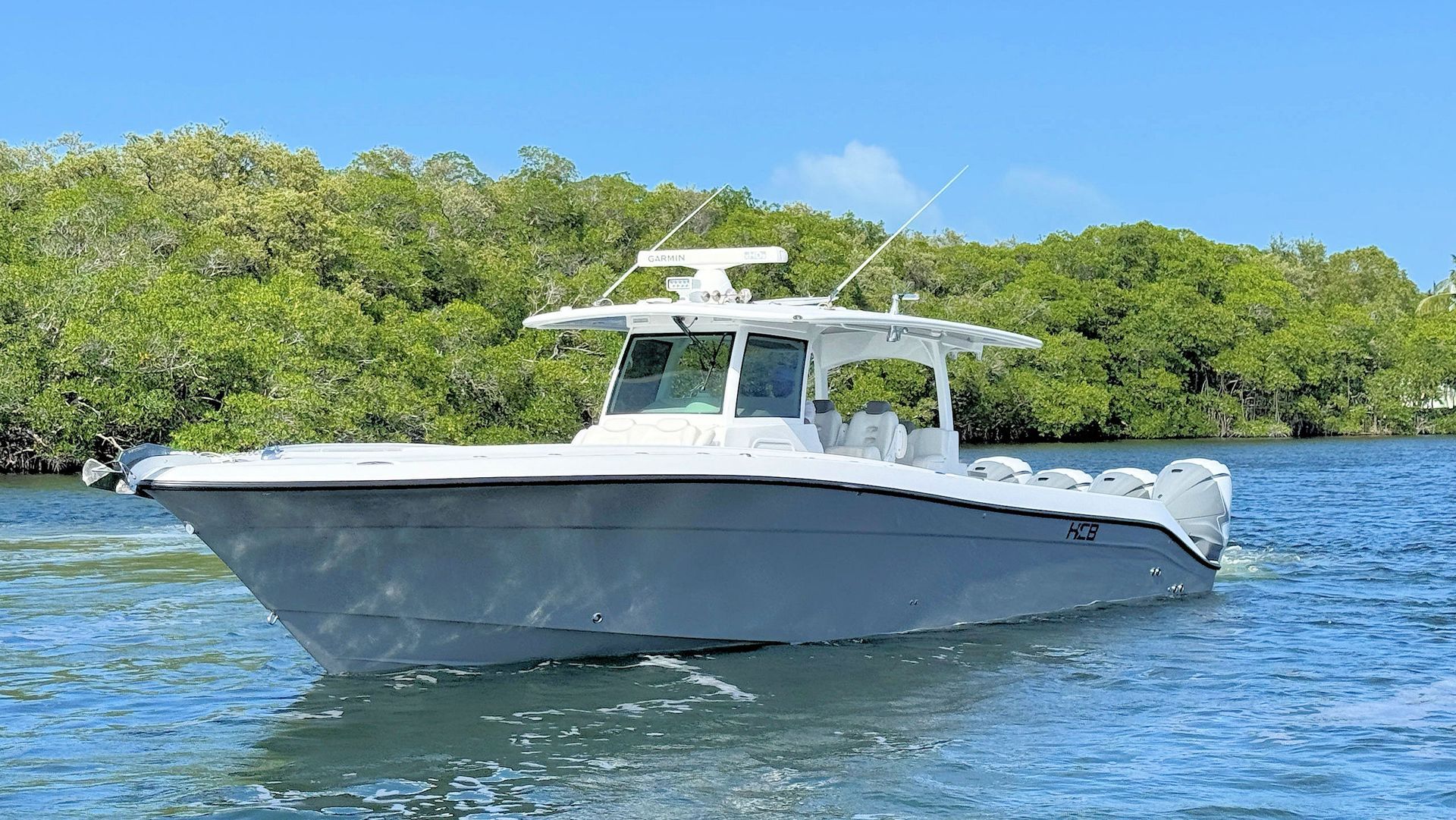 Center console fishing boat on blue water near green mangroves under a clear sky