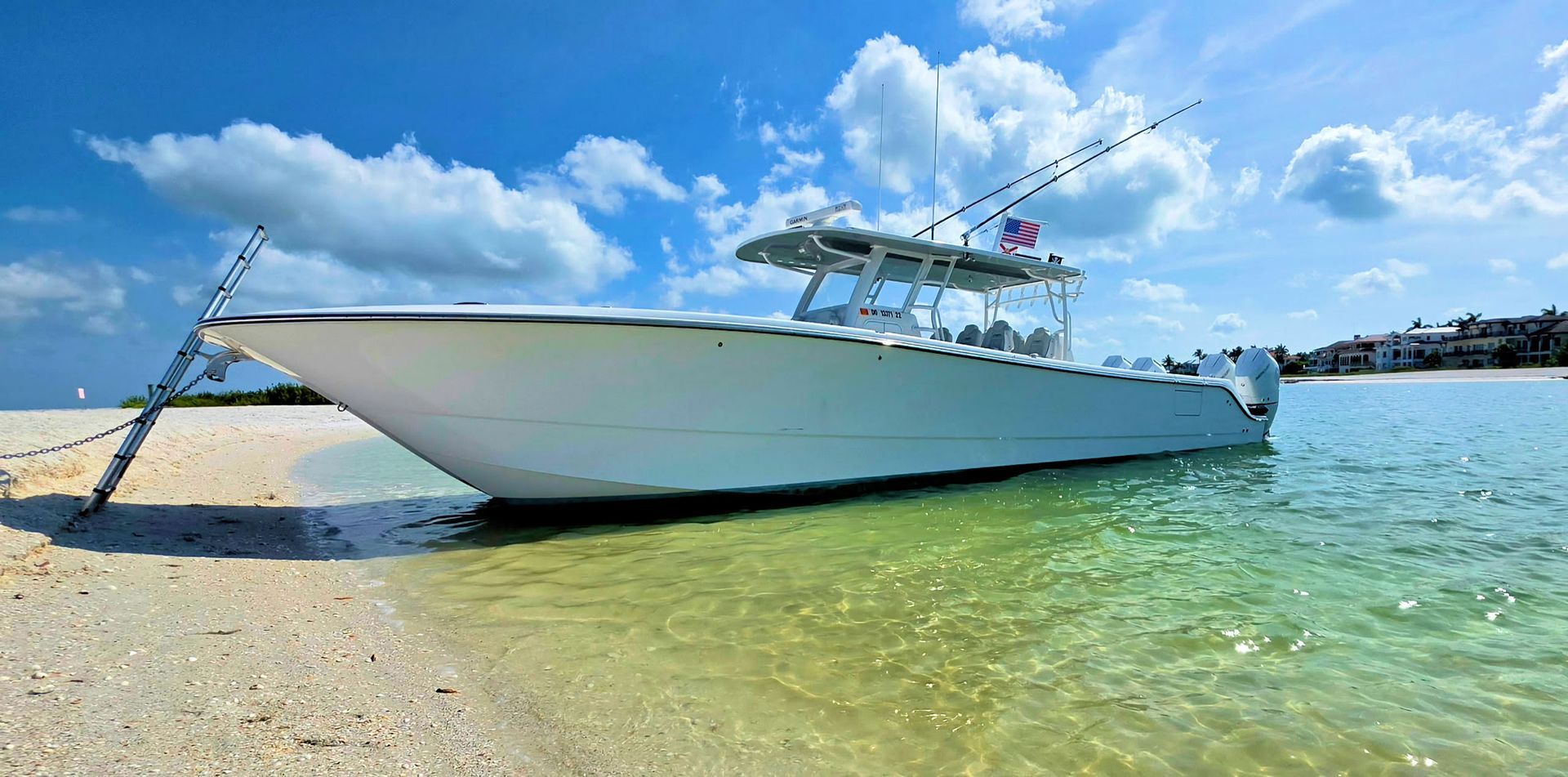 White center console fishing boat on a sandy beach in clear turquoise water under a blue sky