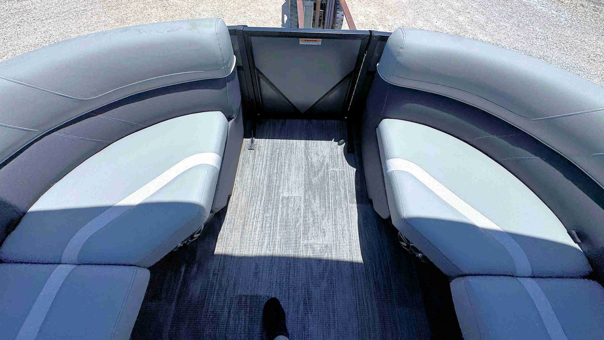 Interior of a Tritoon boat with cushioned seating and a central carpeted walkway.