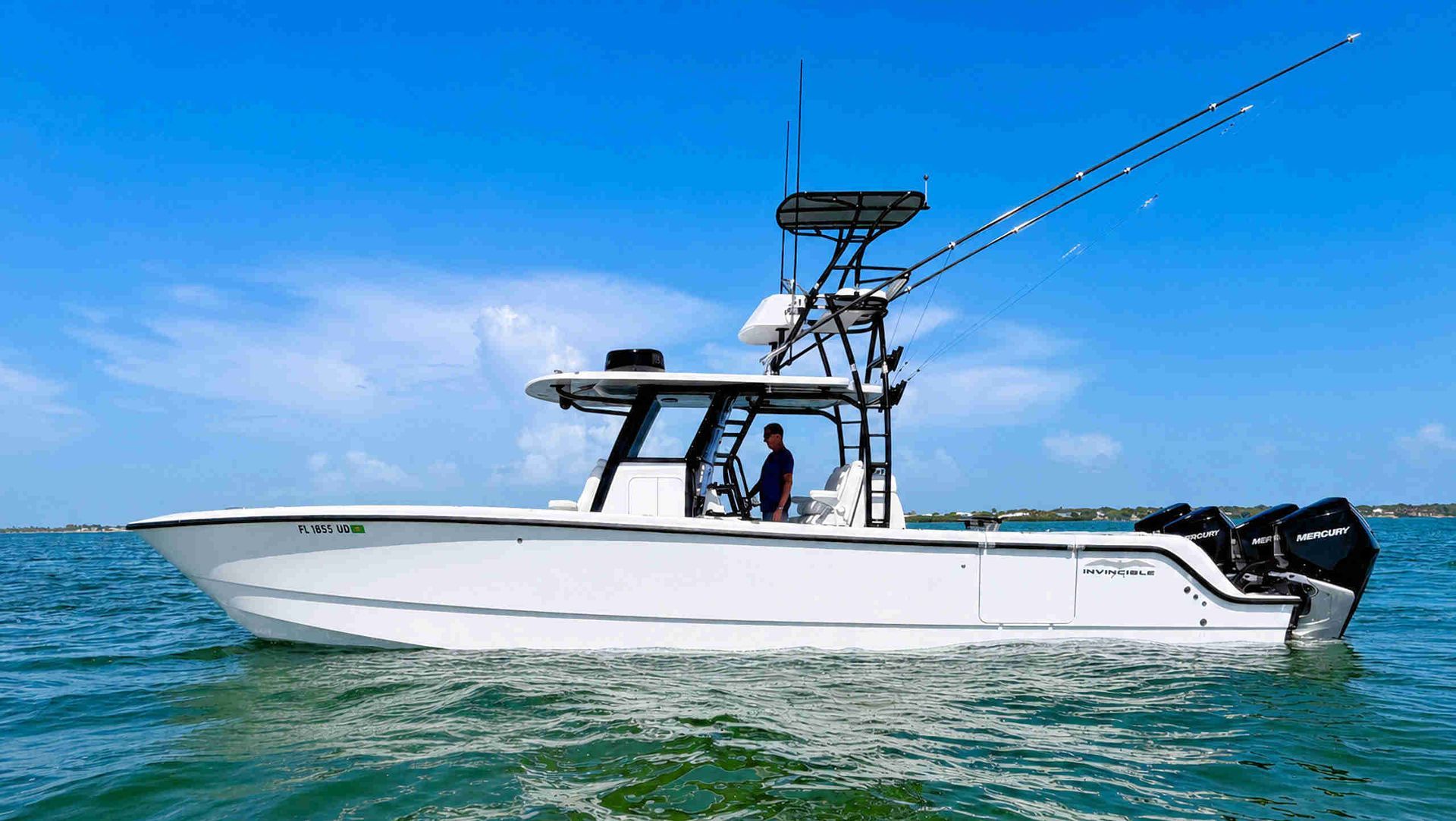 White catamaran center console fishing boat on blue water with fishing rods and tower, under clear sky