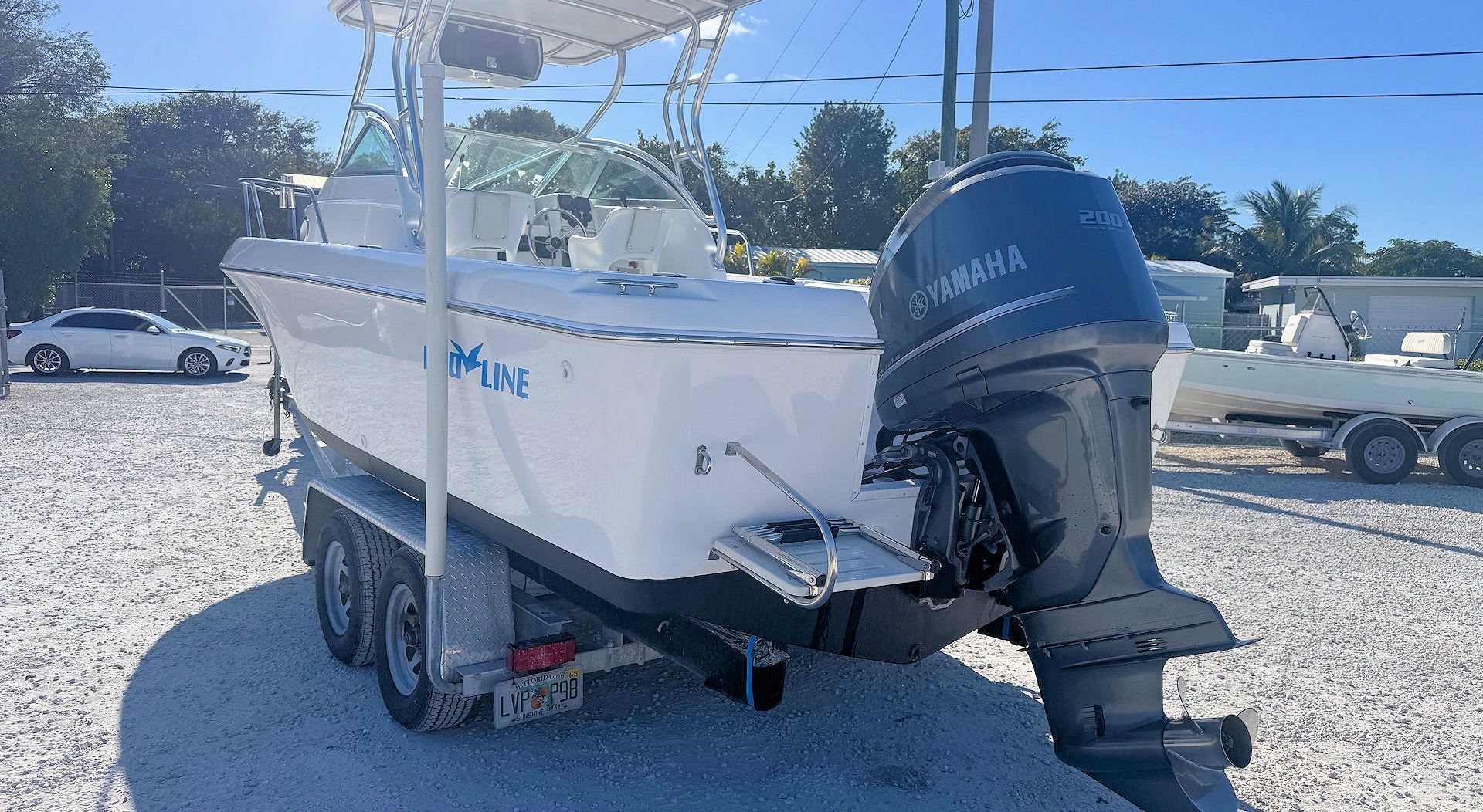 A white Pro-Line dual console boat on a double-axle trailer, powered by a Yamaha outboard motor, in an outdoor lot.