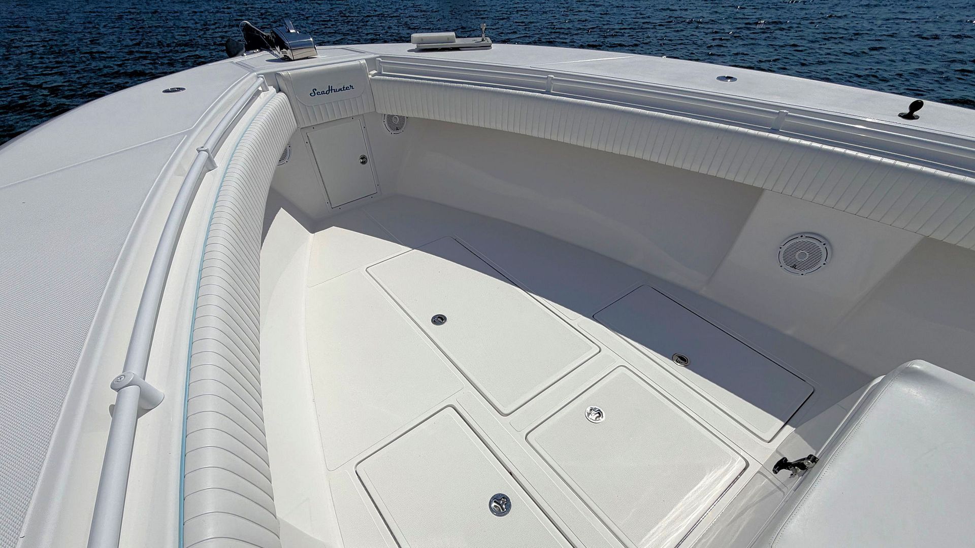 White boat deck with storage hatches and railing beside open water