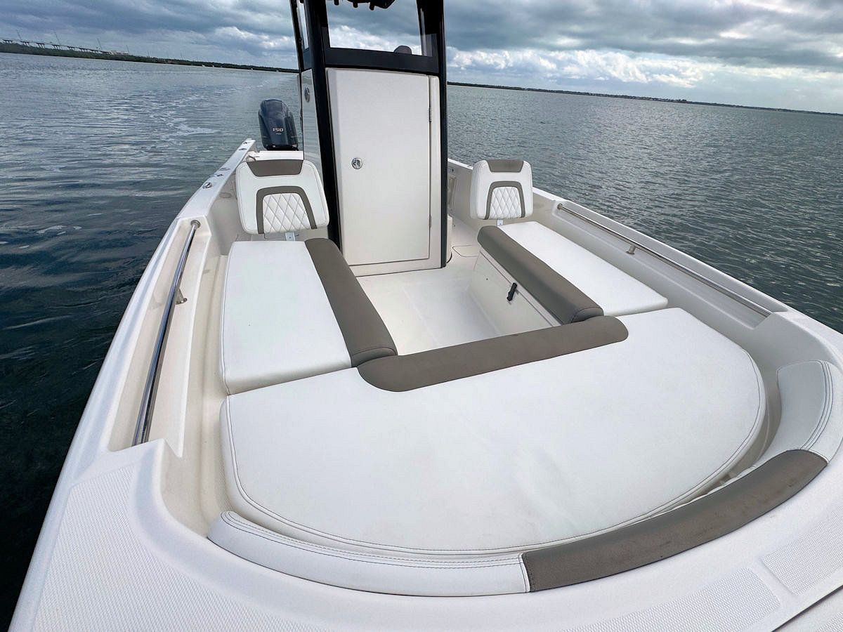 White motorboat interior with white and grey cushions. Overcast sky and water visible.