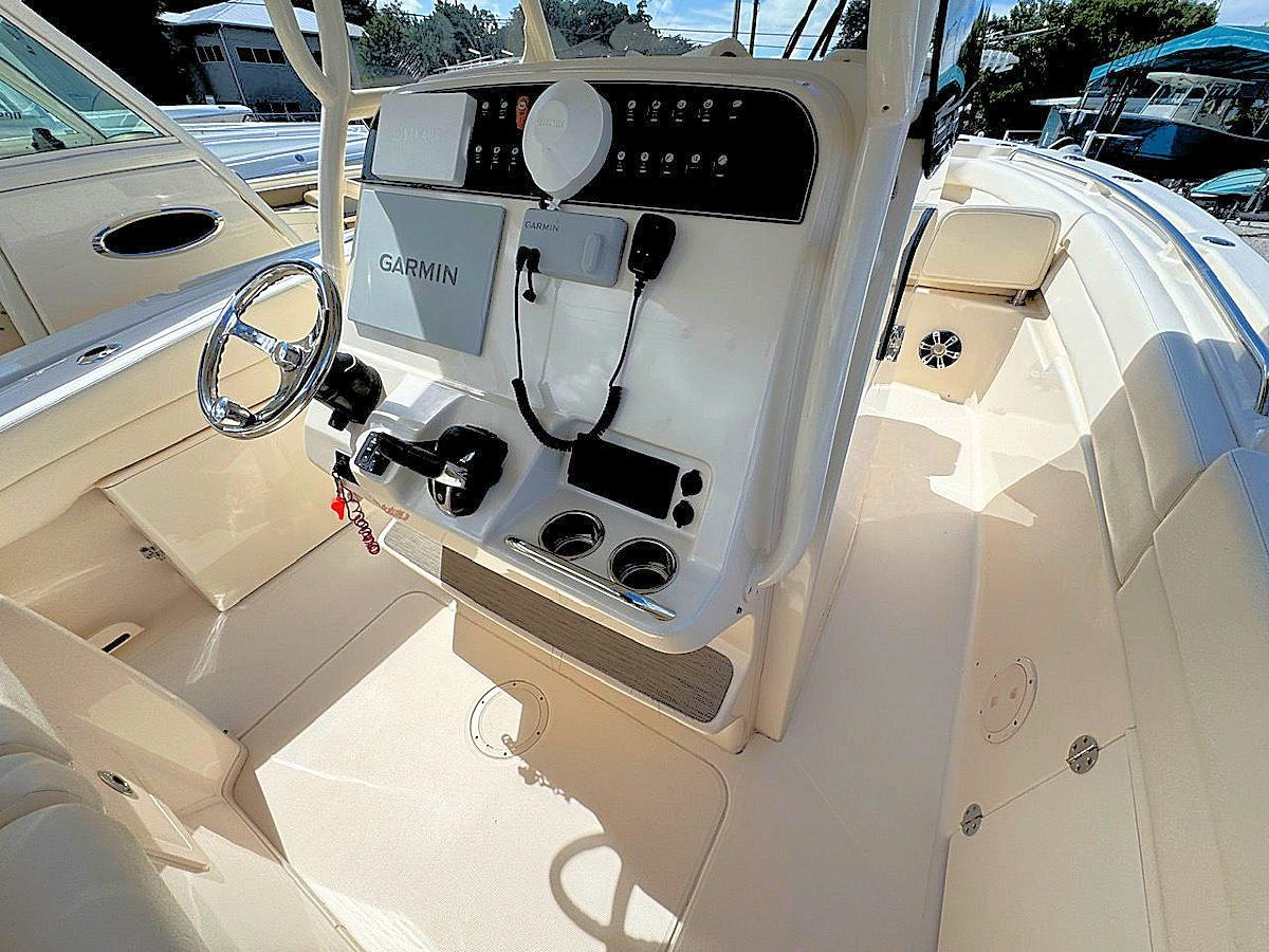 Boat's beige dashboard with navigation displays, steering wheel, and radio controls. Bright outdoor setting.