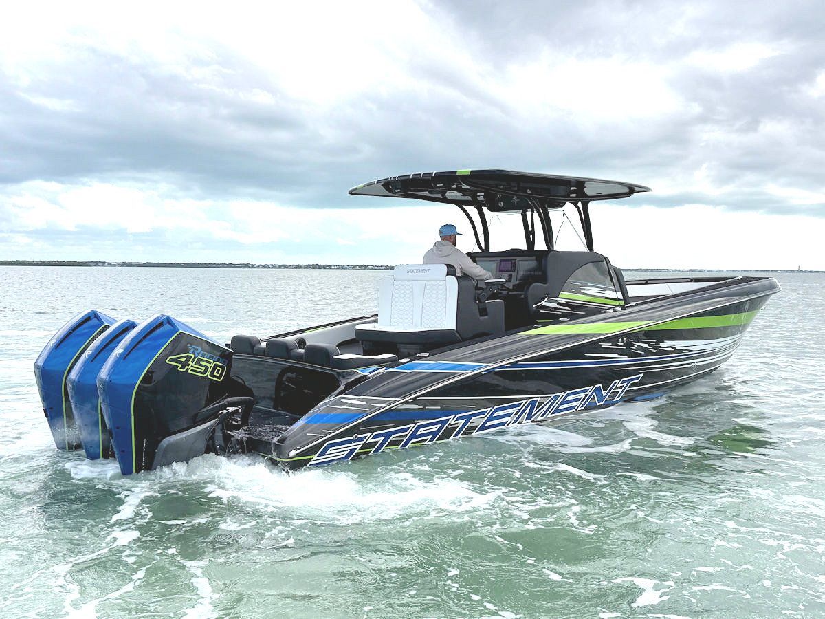 High-speed boat with four blue engines, black hull with green and blue accents, operating on the water.