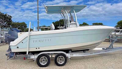 Light blue and white boat on a trailer, under a partly cloudy sky.