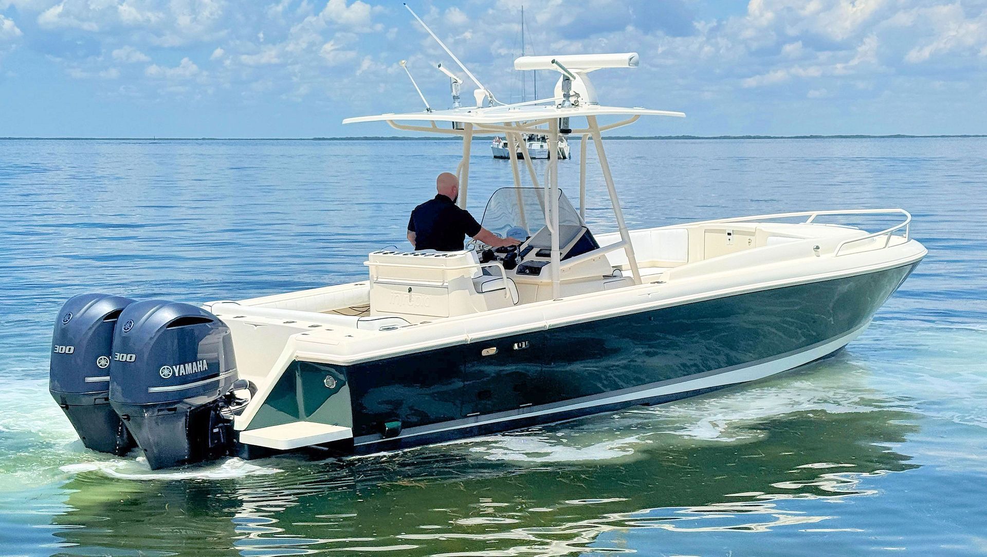 White and navy center console fishing boat with twin outboard motors on calm blue water